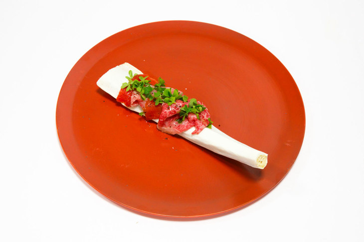 6皿目の「骨と肉」。水分を抜いたスイカとバーナーで軽くあぶった万葉牛ランプをラズベリービネガーやオリーブオイル、塩で味付けし、骨の上に盛り付けている。