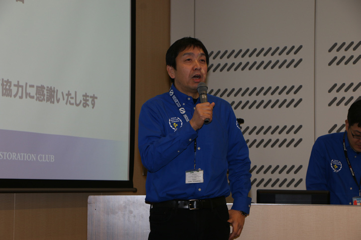 再生完了宣言式でマイクを握る、日産名車再生クラブ代表の木賀新一氏。