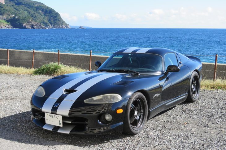 稲取の海を背景にちょいと記念撮影。長～いフロントノーズに小さなキャビンを組み合わせたFRの2シーターは、皆どことなく飛行機を思わせる趣がある。……ありますよね？