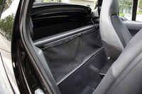 シートの後ろは小さなかばんが置ける程度。運転席と荷室の間仕切りは取り外しができ、助手席のシートバックを前に倒せば荷室から長尺物を積むこともできる。