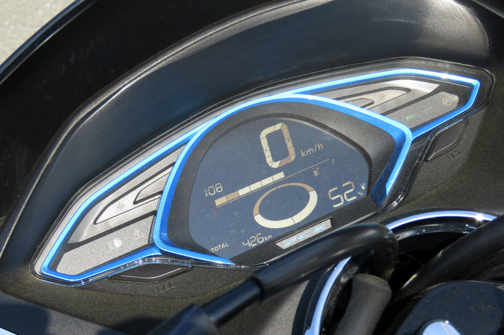 反転液晶表示の「PCXエレクトリック」専用デジタルメーター。車速や時間などに加え、バッテリーの残量や、走行システムが出力制限モードとなったときに点灯する出力制限のインジケーター、充電中に点灯する充電インジケーターなどが表示される。