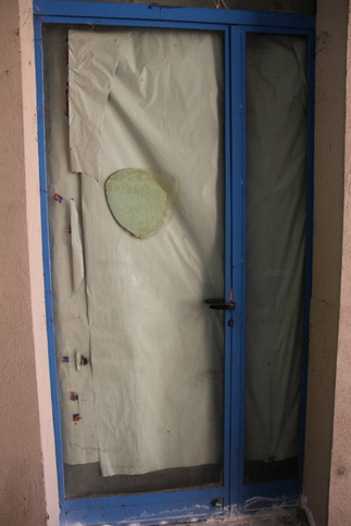 おもちゃ店の閉鎖されたドアには、明らかにランチアのマークだったと思われるステッカー跡が。