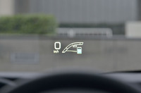 ヘッドアップディスプレイ装着車の前方視界。車速のほかに、ハイブリッドシステムインジケーターや運転支援システムの情報、（純正ナビ装着の場合は）カーナビと連携したルート案内などが表示される。