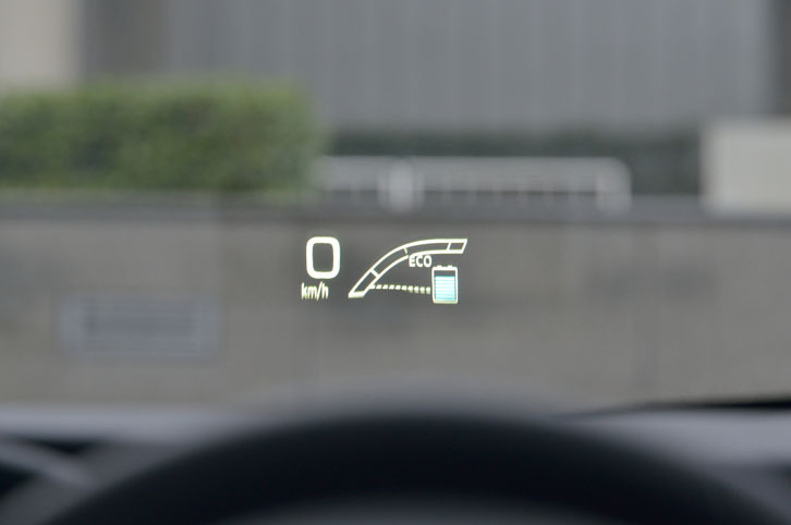 ヘッドアップディスプレイ装着車の前方視界。車速のほかに、ハイブリッドシステムインジケーターや運転支援システムの情報、（純正ナビ装着の場合は）カーナビと連携したルート案内などが表示される。