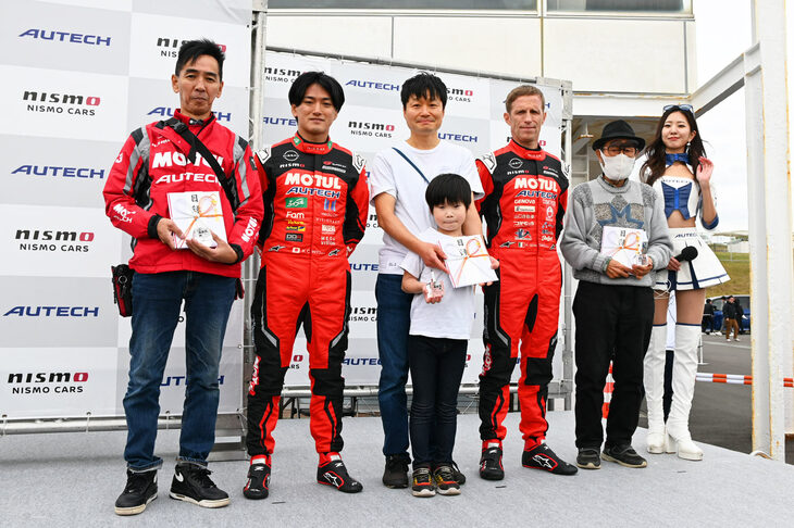 今回のゲストと、毎度恒例の3賞……走行距離の多いクルマのオーナーに贈られる「過走大将」、北東／西南それぞれの最遠方から来た人に贈られる「遠来賞」……を受賞したお三方。写真向かって左から、佐賀県からの参加で「遠来賞」を受賞したKuronekoさん、千代勝正選手、北海道・室蘭市からの参加で「遠来賞」を受賞したぬまっちさん親子、ロニー・クインタレッリ選手、オドメーターが39万4871kmで「過走大将」を受賞したぬまっちさん、AUTECHレースアンバサダーの高岡みほさん。