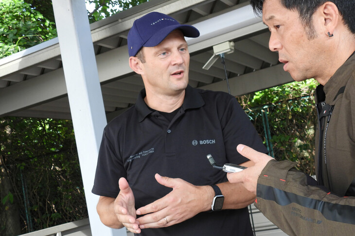 地図データを活用したライディングアシストシステムについて筆者に説明する、ボッシュのゲオルギ・アンドレアス氏（写真中央）。細かい話はできないが、ARASの次なる展開を感じさせる体験をさせてもらった。