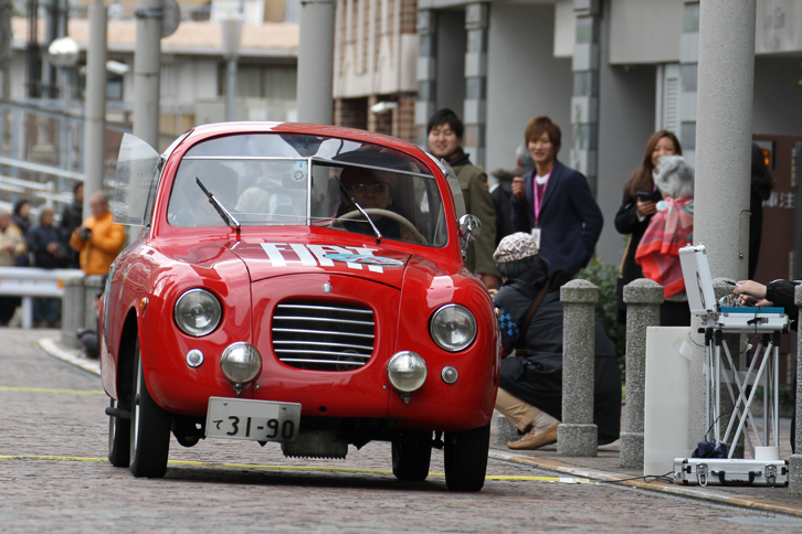 1947年「フィアット500Bザガート パノラミカ」。通称トッポリーノこと初代「フィアット500」のシャシーにザガートがボディーを架装した愛らしいモデル。路面に貼られた黄色い線がPC競技用のセンサーで、画像右端でスタッフが測定している。