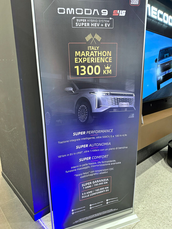 「オモダ9」の4WDハイブリッド仕様の特徴を説明する“のぼり”。航続距離は約1300km。保証期間は7年もしくは15万kmだが、高電圧部品については8年もしくは16万kmをうたう。