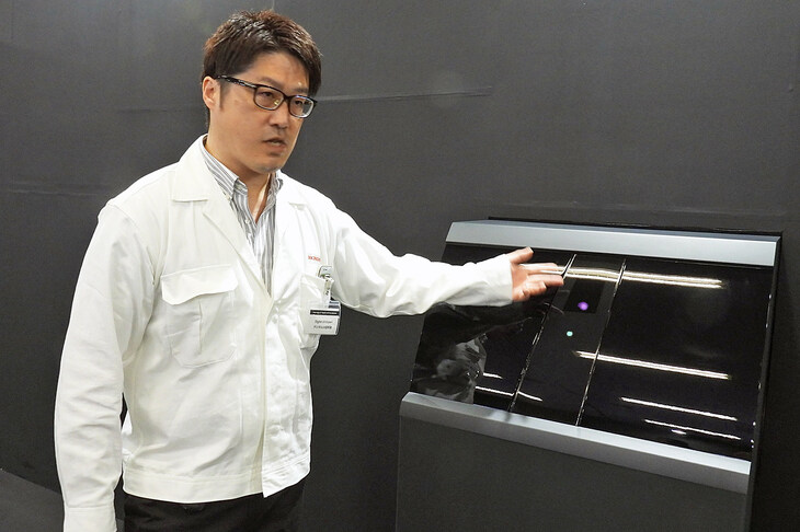 「先読みシームレスエントリー」ことドアの自動オープン機能について解説するホンダのスタッフ。写真の展示は車両のBピラーを模したもので、ここに自車側方の状況を監視するカメラが備わっている。