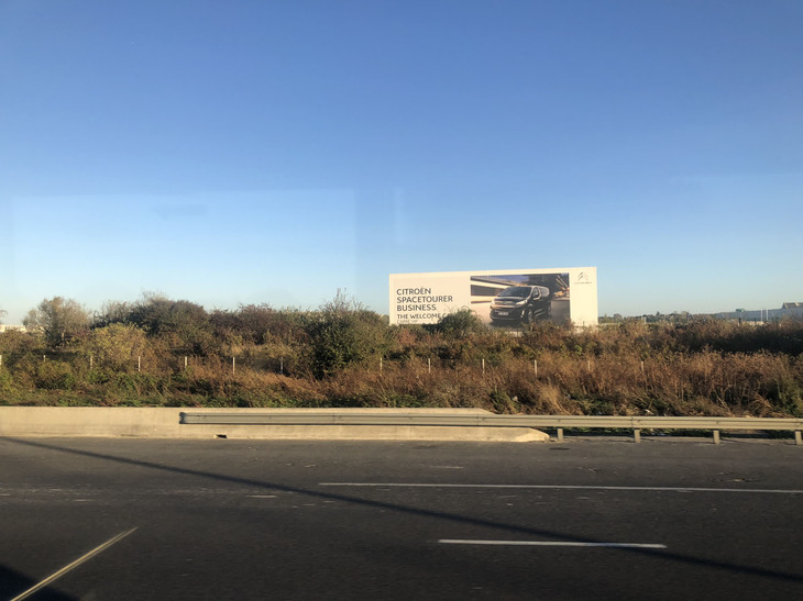 シャルル=ド=ゴール空港に向かう途中の車内から。閉鎖されたPSAオールネー・スー・ボワ工場跡には、ミニバン「シトロエン・スペースツアラー」の看板が立っていた。
