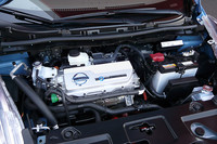 「エンジン？」と思わせるカバーが目立つ、フロントボンネット内の様子。