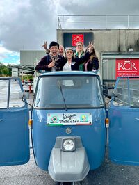 イタリアを代表するクリスタルガラスの産地、コッレ・ディ・ヴァルデルサの工場直売所にて。店長（写真中央でピースしている人物）と、イベント参加者の到着を先回りして待つ筆者（向かって左端）。