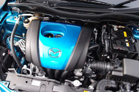 これが1.3リッターの高圧縮型ガソリンエンジン「スカイアクティブG 1.3」。青いエンジンカバーが、特別なエンジンの証しだ。