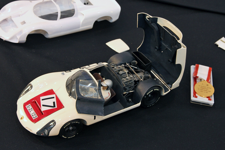1971年の第1回モデルカーコンテストの入選作という、タミヤの1/12「ポルシェ・カレラ10（910）」。製作当時高校1年生だった作者が、保存していた入選作をレストアしたものという。入選者には写真右の記念メダルと賞金1万円が贈られたそうで、作者いわく「当時の高校生にとって1万円は大きく、ありがたかった」とのこと。ちなみにカレラ10のキット価格は1800円だった。