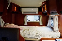 リアに備わった巨大なベッド。最近のキャンピングカーは家庭用エアコン装備で真夏でも涼しい！ しかし当然値段は張る。