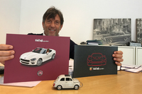 熟練セールスマンのフランチェスコ・タッデオさん。仕事用パソコンで旧型「500」のマウスを愛用。後方には、「フィアット2300」など1960年代の広報写真パネルが。