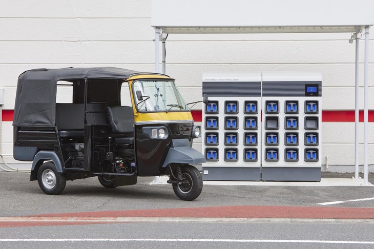 インド国内で使われている電動の三輪タクシー「E-AUTOリキシャ」。奥に見えるのは、ホンダが開発したバッテリー交換ステーション「Honda Mobile Power Pack Exchanger e：」である。