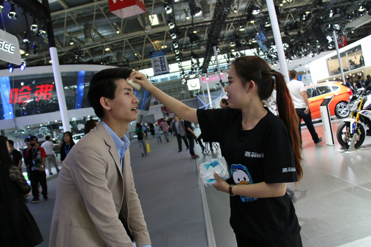 北京モーターショー初日の気温は30度。汗を拭いてもらうMINIの男性コンパニオン。