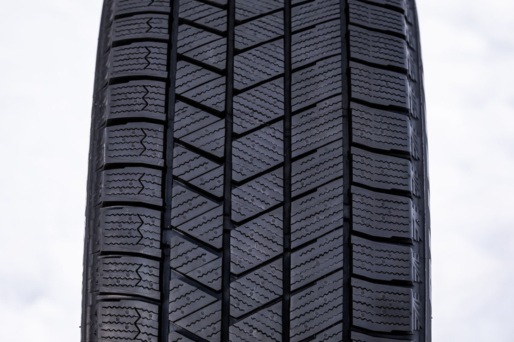 “突起付きブロック”や“端止めサイプ”などを用いた新トレッドパターンを採用し、従来品に対し氷上でのブレーキ性能が20％向上。トレッド変形の抑制と接地圧の均一化も図り、摩耗ライフも17％向上させている。