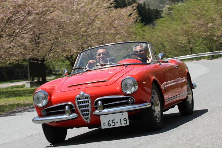 オープンエア・ドライブを満喫する1963年「アルファ・ロメオ・ジュリア スパイダー」。「ジュリエッタ スパイダー」のボディーに1.6リッターエンジンを積んだモデル。