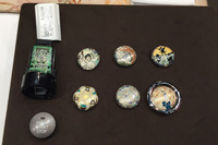 室田さんがクルマのエンジンスタートスイッチ用に制作した薩摩ボタン。九州の交通安全の神様をモチーフにしたものや、「発進」の“發”をあしらったものなど、さまざま。
	 
	