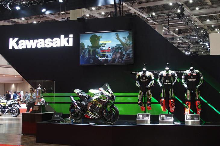 2019年の鈴鹿8時間耐久ロードレース優勝車「ニンジャZX-10RR」とチームのライダーが着用したレーシングスーツを展示。上部のモニターには、同レースの走行シーンや勝利を喜ぶチーム様子が映し出されていた。