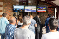 パーティー会場のモニターにて、各クラス上位8台の車両によって競われる最終予選「ハイパーポール」の様子を見守るツアーの参加者。