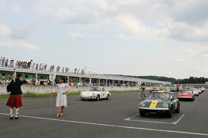 最終レースとなる、1960～69年の量産スポーツカーが10周を競うエバーグリーン・カップ決勝のスターティンググリッド。このレースに限らず、各レースともスタート前にはグリッド上でバグパイプが演奏される。生沢 徹さんの1968年「ポルシェ911T」を抑えてポールポジションを獲得したのは、ほぼ毎回、彼とトップを争っている関口好夫さんの1966年「ロータス26R（レーシングエラン）」。