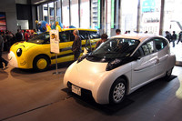 会場に展示されたSIM-Drive製EV「SIM-LEI」（手前）と、ベネッセこどもちゃれんじ20周年記念の「しまじろうカー」。