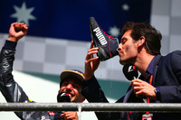 フェラーリの2台と僚友フェルスタッペンのスタート直後の接触により前が開けたリカルド（左）は2戦連続の2位表彰台を獲得。おなじみになりつつあるドライビングシューズでシャンパンをいただく“奇行”を、インタビュアーとして登壇した母国オーストラリアの先輩、マーク・ウェバー（右）にもさせる暴挙（!?）に出た。ドライバーズチャンピオンシップで3位を守っている。（Photo=Red Bull Racing）