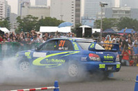 ソルベルグに負けじと派手にタイヤスモークを上げながらスピンターンをキメる新井選手。ナビシートには抽選で当ったファンが乗っているんだけど……。