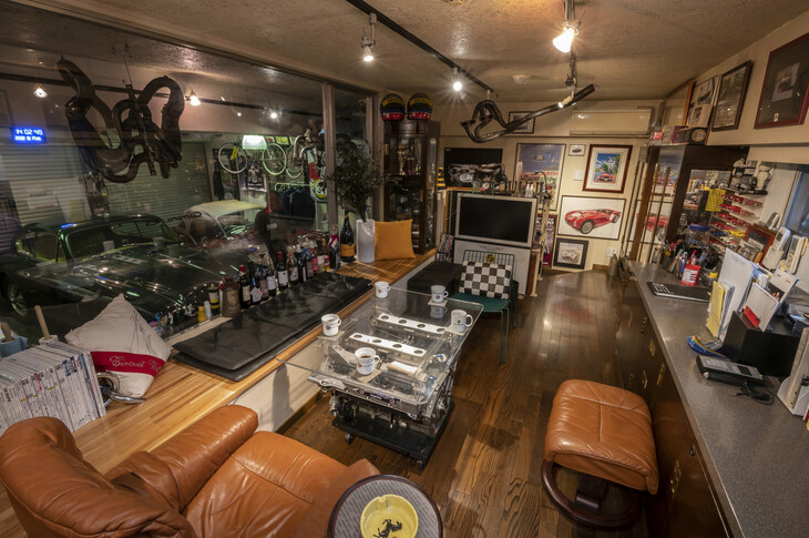 ガレージとは窓付きの壁で仕切られたリビングルーム。数々のトロフィー、ミニカー、懐かしの記念写真などなどは“お約束”。