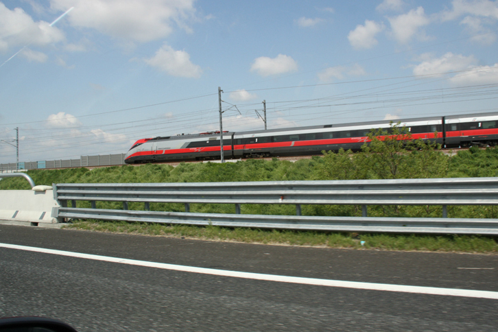 「太陽の道」では、たびたび高速鉄道と並行して走る。写真の列車は「Freccia rossa（フレッチャロッサ）号」。フレッチャロッサとは「赤い矢」。イタリア版レッドアロー号である。