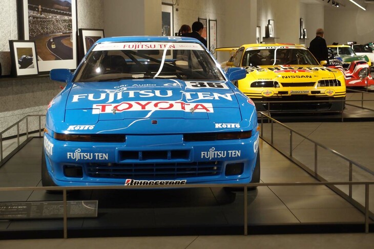 「フジを彩ったツワモノ・マシン」というテーマで並べられた、「トヨタ・スープラ ターボA」（1990年）と「日産ペンズオイルNISMOスカイラインGT-R」（1998年）。