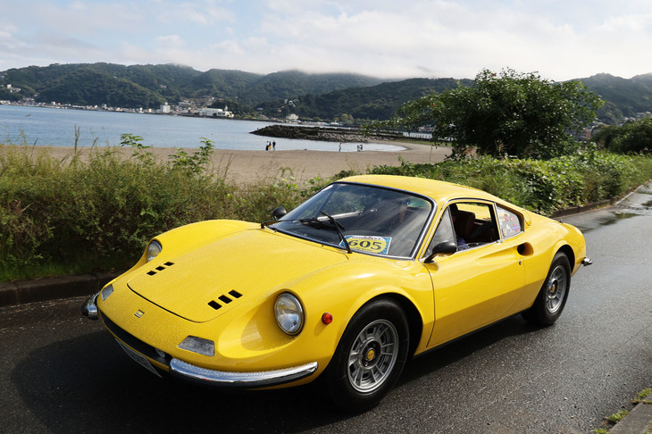 自由参加のオプションであるツーリングに向かう、あるいは帰宅すべく参加車両が砂浜沿いの周回路を通って長浜海浜公園から退出しようという午後1時前後には、ご覧のような好天となった。空と海の青に鮮やかなイエローが映える1972年「ディーノ246GT」。