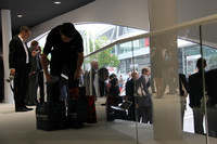 捨てられた報道資料のカバーなどを手提げ袋に集める清掃スタッフ。