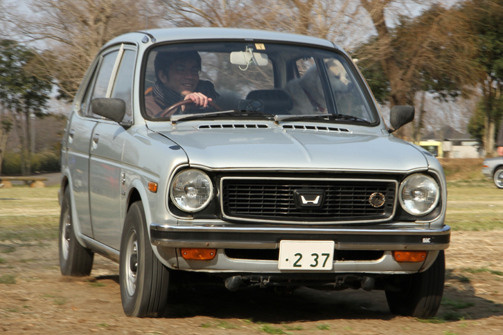 後席から顔をのぞかせている犬がかわいい1973年「ホンダ・ライフ」。タイミングベルト、バランスシャフト、そしてジアコーザ式FFといったメカニズムを日本車としては初採用し、初代「シビック」の土台ともなった軽乗用車である。フロントグリルはツインキャブエンジン搭載の「2ドア・ツーリング」用。