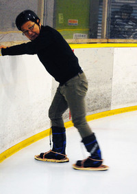 氷上で恐る恐る特製かんじきを試す筆者。ヘルメットに頭が入っていないのはご愛嬌（あいきょう）。