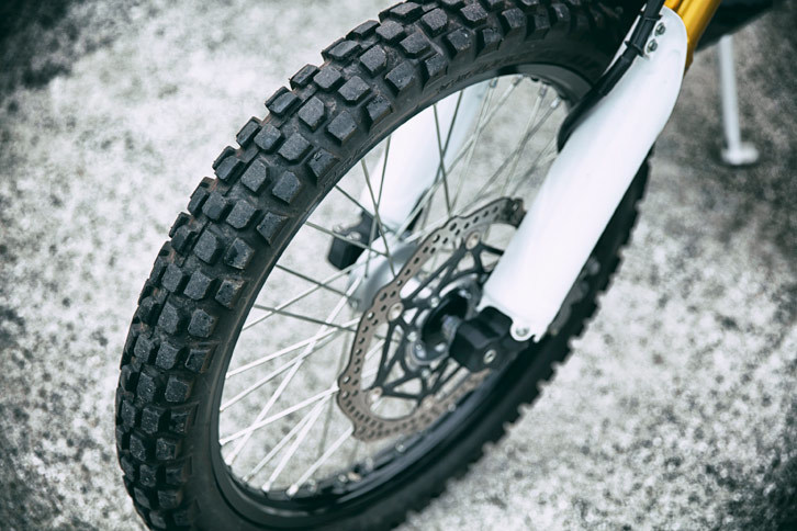 オフロード走行を考慮したブロックパターンのタイヤ。剛性の最適化と優れたハンドリング性能を実現するため、新開発のフロントフォークが採用されている。