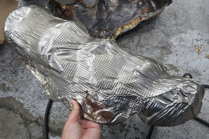 メカさんいわく、「穴の原因は遮熱板との接触による“電食”では？」とのこと。こちらがその遮熱板。一見キレイに見えるが……。