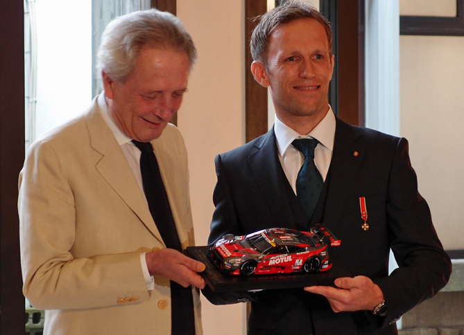 勲章のお返しに、クインタレッリ氏からジョルジ大使に、自身が駆るレーシングカーのミニチュアが贈られた。「子どものような、うれしい気持ちになりますね」と、大使もご満悦の様子。