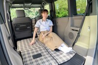 リアシートを折りたたんだ荷室スペース、通称「ふらっとテラス」でくつろぐ松村さん。荷室を“くつろぎ空間”とするのにあたっては、さまざまな素材を車内に持ち込んで、アイデアを膨らませたという。
