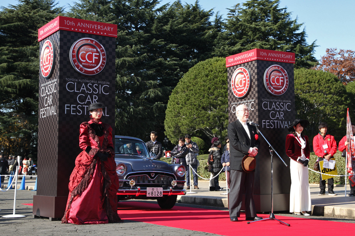 オープニングセレモニー。来賓代表としてあいさつするのは、自動車史家の高島鎮雄氏。ゲートには毎回パレードを先導しているトヨタ博物館所蔵の1960年「トヨペット・クラウン・デラックス（RS21）」が控えている。