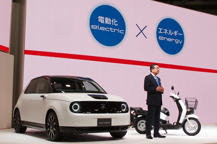 2019年の東京モーターショーにおいて、「ホンダe」と「ベンリィe：」を紹介する本田技研工業の八郷隆弘社長。八郷社長はこのとき、ベンリィe：の発売に合わせて二輪車用コネクテッドサービスの導入についてもアナウンスしていた。