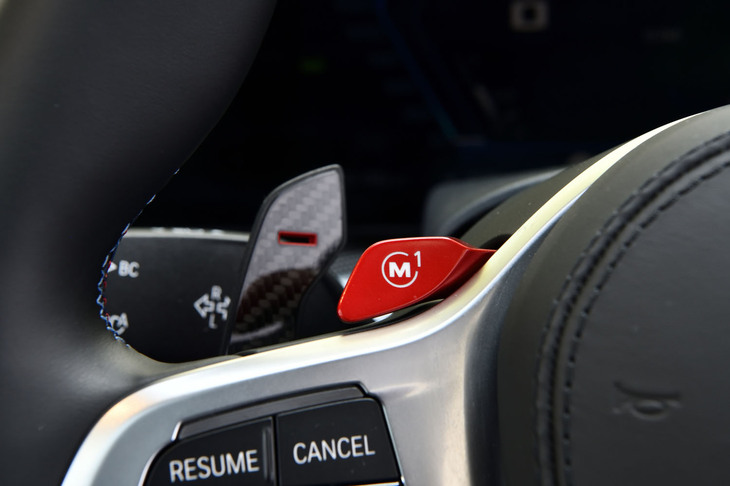 好みのセッティングをダイレクトに呼び出すことができるショートカットスイッチ「M1」「M2」を、ステアリングスポークの左右に配置。その奥には「X6 Mコンペティション」専用のカーボン製シフトパドルが控える。