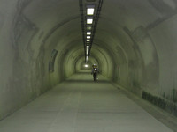 こういうトンネルもある。愛媛県に二つある歩行者専用トンネル。国道56号線の、既存のクルマ用トンネルに並行して建設されたこれは、中学校の統廃合に伴って、通学の安全のために作られたと聞く。だが、無機質な蛍光灯が真っ白な壁を浮かび上がらせるこの奇妙な空間では、誰一人として会う人はいなかった。ここまで投資するよりも、既存のトンネルをより安全に改善する方が、合理的だったと思う。
写真でわかるように、私たちは体や荷物の目立つ場所に反射テープを貼って自衛していた。