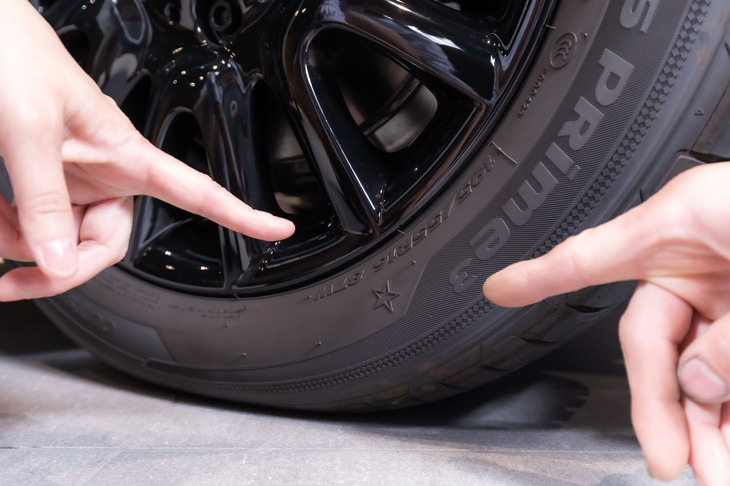 吉田さんの愛車のタイヤを前に「ここにスターマークがありますね」と山﨑氏。「MINI本来のパフォーマンスを長くお楽しみいただくために、こまめな空気圧のチェックも重要です」と言う。