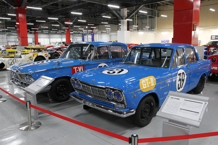 1964年の第2回日本グランプリのGTレースで、「ポルシェ904カレラGTS」を一瞬だがリードしたことから「スカイライン伝説」を生んだ「プリンス・スカイラインGT」（S54A-1、手前）と、T-IV（ツーリングカー）レースで優勝した「プリンス・グロリア スーパー6」（奥、S41D）。スカイラインGTはレースを走った個体ではなくレプリカだが、ホンモノと同様に、グランプリ出場のホモロゲーション取得のために急造された100台のうちの1台をベースに作られている。