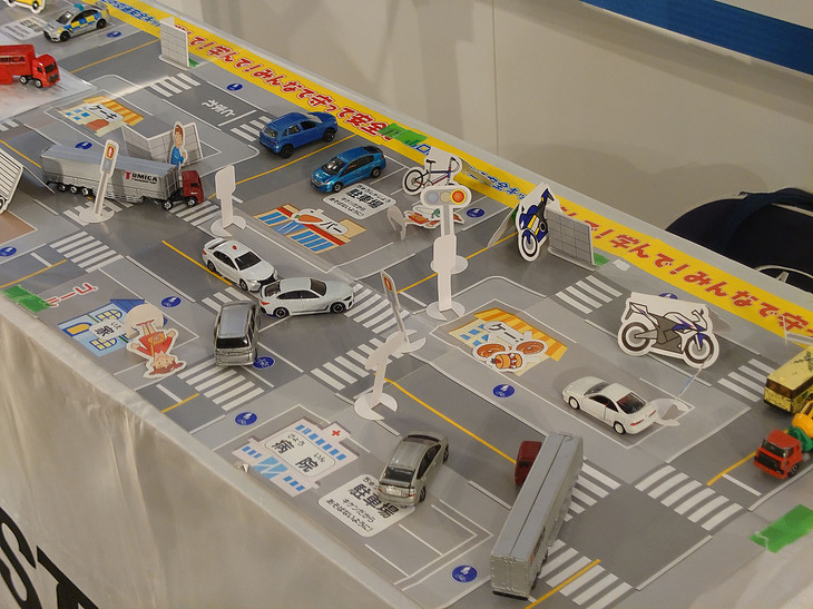 参加者に配られたグッズのひとつが、交通ルールが学べるマップだ。トミカサイズのミニカーで遊べるもので、立体的な壁なども付属。子どもたちがミニカー遊びを通じて、トラックの内輪差がもたらす危険性や、塀などの障害物がドライバーにとって死角になることを学べる。