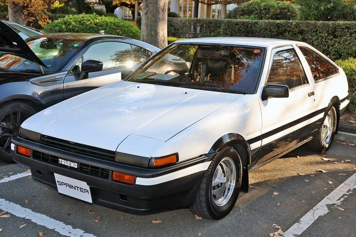 「トヨタ・スプリンタートレノ」の3ドアハッチバック。マンガ『頭文字D』で高い人気を誇る前期型パンダカラーのAE86だが、まるで新車のような美しい状態を保つ。最近では、見かけなくなったオリジナルアルミホイールが懐かしい。